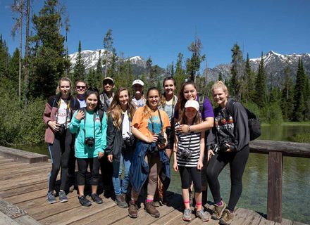 students stand on a bridge with mountains in the background