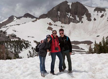 three students smile on top of a snowy mountain