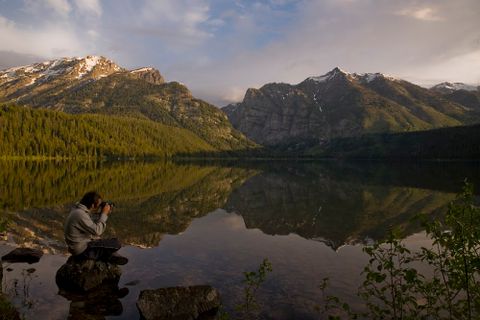 a student sits on the edge of a mountain lake