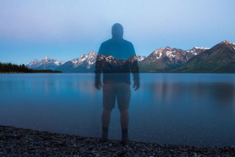 translucent figure standing in front of a lake