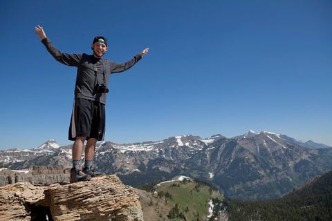 a student with outstretched arms on a mountain